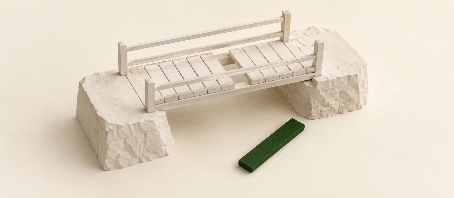 A cream study model of a small plank footbridge over a gap with one plank missing and lying loose beside it, with the loose plank in green.