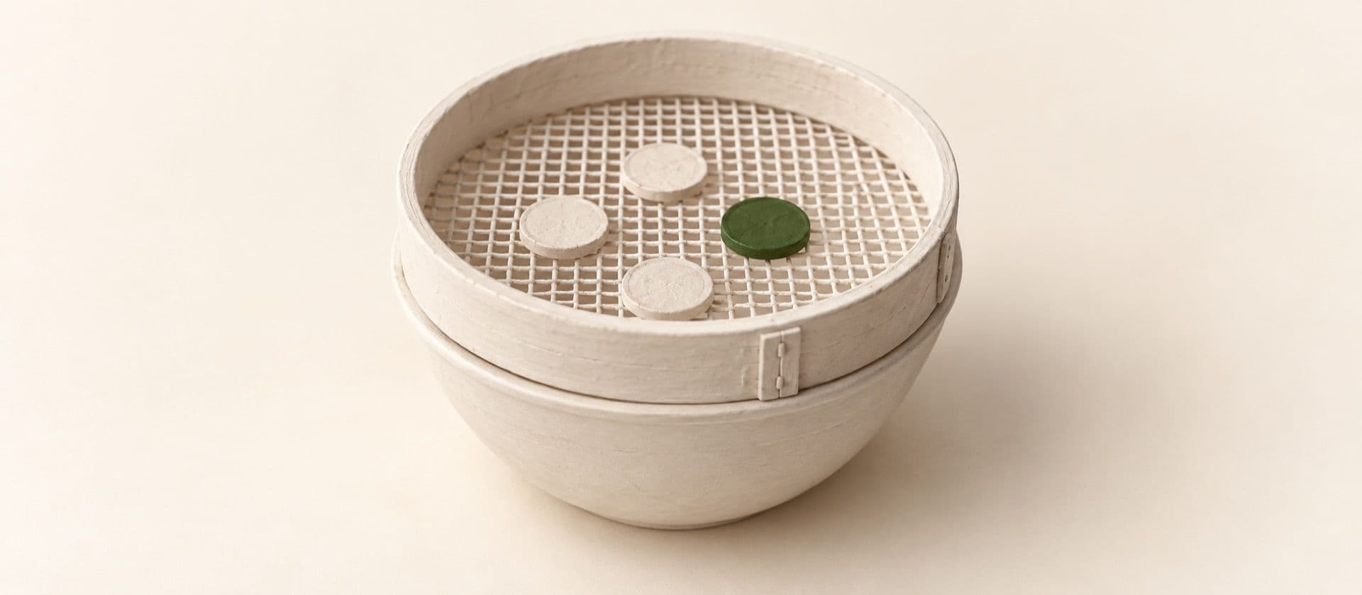 A cream study model of a round sieve resting on a bowl, a few coins caught in the sieve, with one coin in the sieve in green.