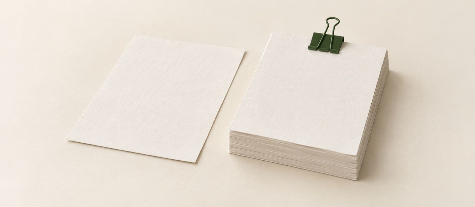 A cream study model of two documents side by side: a single loose blank sheet, and a thick bundle of blank sheets held by a binder clip, with the binder clip in green.