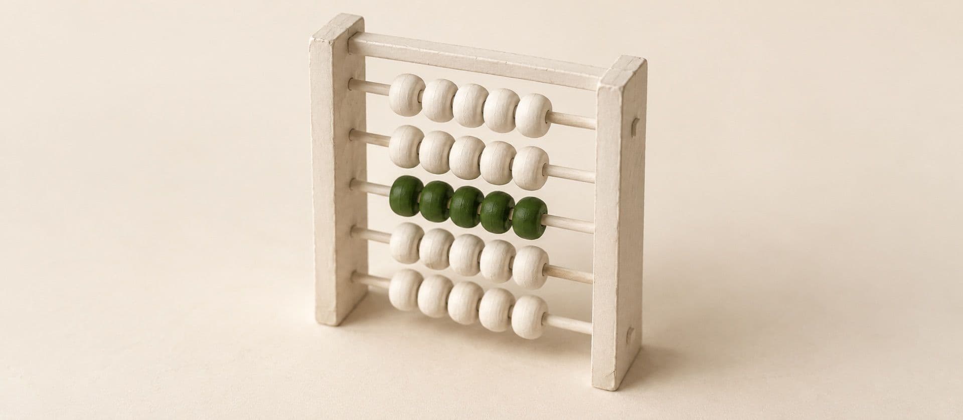 A cream study model of a wooden-frame abacus with five rods of beads, with the beads on one rod in green.