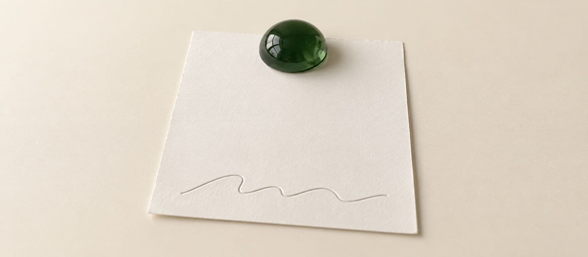 A cream study model of a single blank sheet with a wavy signature line at the bottom, held down by a domed glass paperweight, with the paperweight in green.